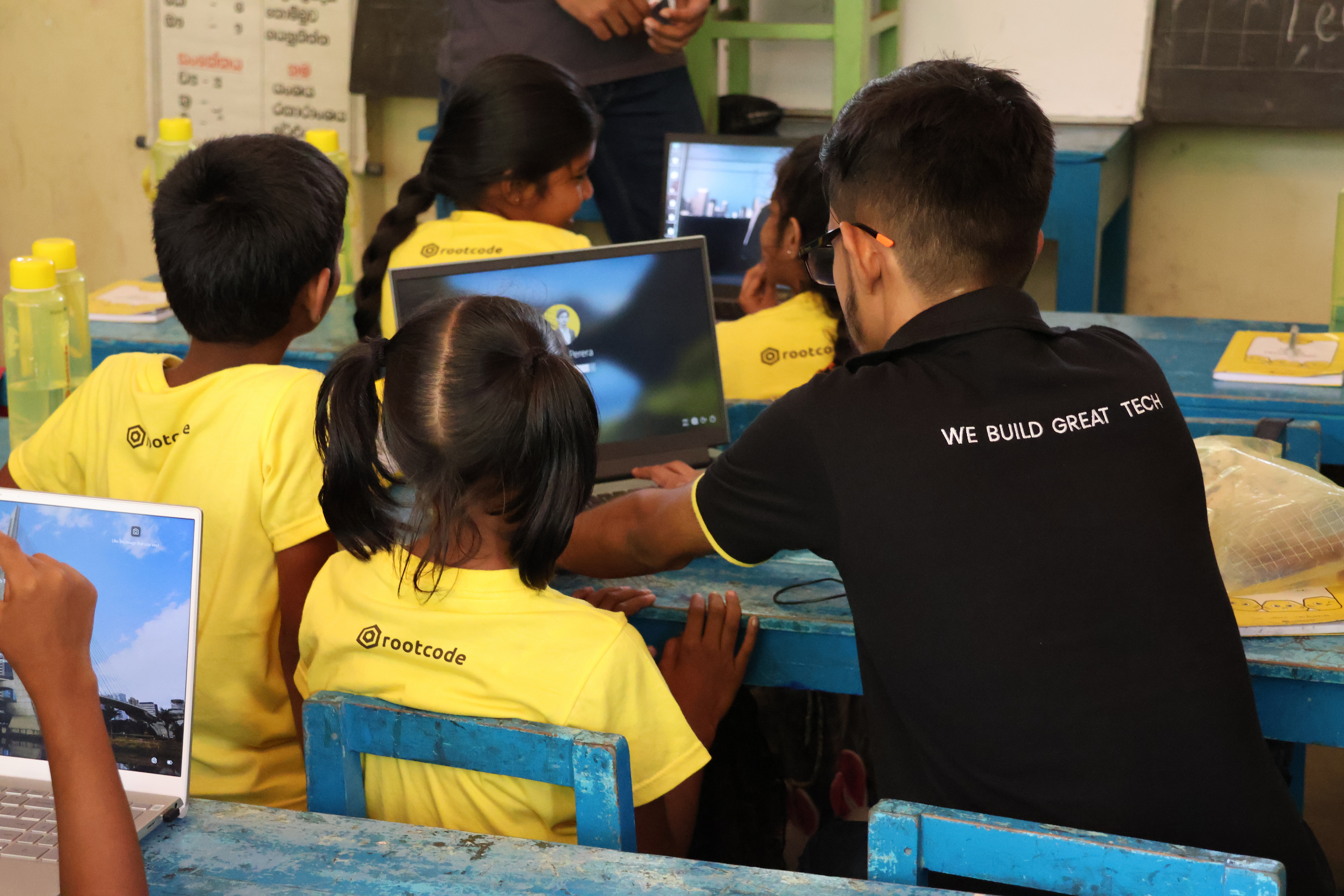 A Rootcoder instructing students on how to use a laptop